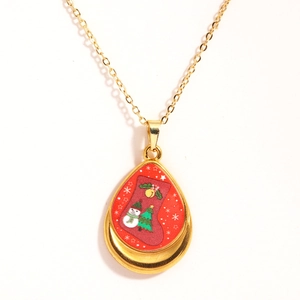 Close-up of gold water drop pendant featuring festive Christmas tree and snowman patterns