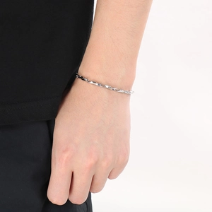 Detail of silver twisted metal chain bracelet worn on wrist for a modern look