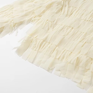 Detailed close-up of layered fringe texture on an off-white long sleeve shirt