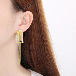 Gros plan de boucles d'oreilles dorées avec cristaux et longues franges en chaîne