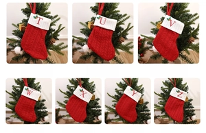 Detailed knit texture of red Christmas stockings with embroidered letters and holly