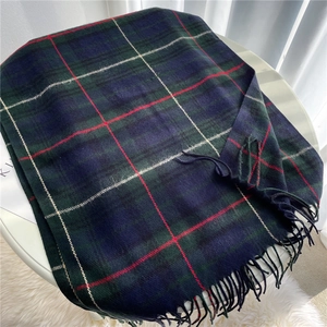 Detailed close-up of navy and green plaid scarf texture with soft tassels on a chair