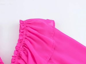 Détail du chemisier en mousseline rose avec volants et décolleté plissé aux épaules nues