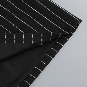 Detailed macro view of black ribbed knit fabric with white rhinestone stripes and stitching