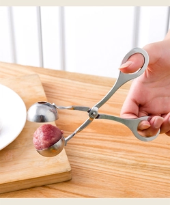 Macro view of handheld stainless steel meatball maker shaping a fresh round meat ball