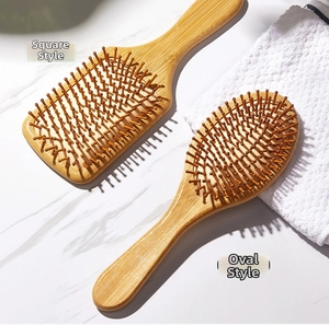 Close-up of square and oval bamboo massage hair brushes on a marble surface