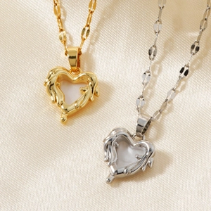 Minimalist heart pendant necklace in gold and silver finish on white silk background