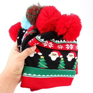 Handheld stack of festive Christmas knit hats with reindeer patterns and pom-poms