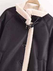 Close-up of black leather jacket featuring shearling lining and metal buckle neck strap