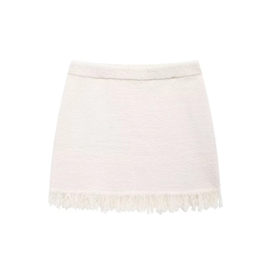 Detail of white tweed knit mini skirt featuring elegant tassel fringe trim on the hemline
