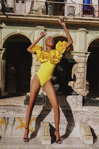 Close-up of vibrant yellow bodysuit featuring a large 3D floral ruffle on the shoulder