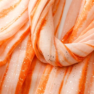 Detailed texture of orange striped scarf with golden foil sequins and soft fringe edge