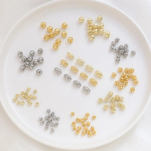 Macro shot of assorted gold and silver metal beads for DIY jewelry making in a white tray