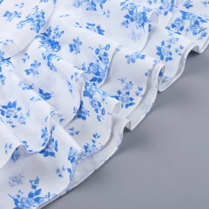 Dettaglio dell'orlo a balze a strati con stampa floreale blu su tessuto bianco