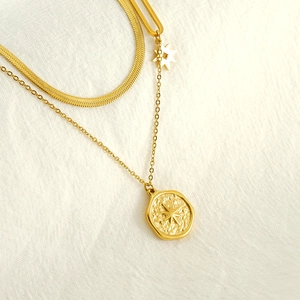 Close-up of golden double-layer necklace with snake chain and star pendant on fabric