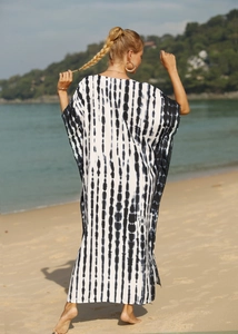 Rear view of a loose black and white tie-dye beach cover-up robe in a coastal setting