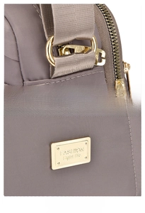Detail of mocha nylon shoulder bag featuring golden metal ring and engraved logo plate