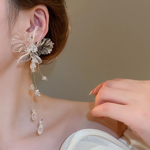 Close-up of transparent flower earrings with crystal tassel dangles on a female model