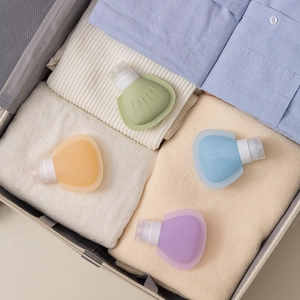 Set of four shell-shaped silicone travel bottles in luggage for organized packing