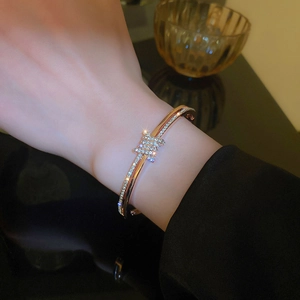 Close-up of rose gold knot bangle featuring micro-pave white zircon inlay on model