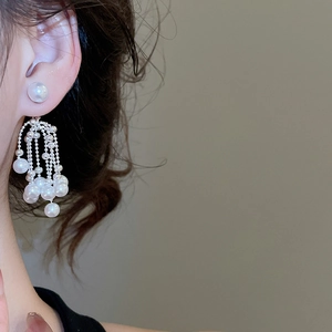 Detail of silver pearl tassel earrings with cascading beads worn by a model gracefully