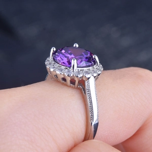 Close-up of a 5-carat oval purple gemstone ring with a brilliant halo setting on finger