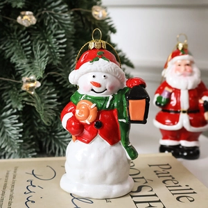 Festive painted snowman ornament with red hat on vintage book with warm holiday lights