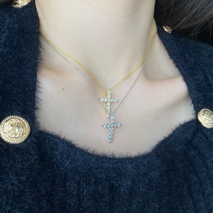 Close-up of gold and silver cross necklaces with micro-pave crystals on a model