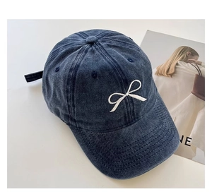 Detail der weißen Schleifenbestickung auf einer gewaschenen blauen Jeans-Kappe