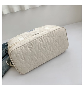 Close-up of cream white travel bag with star quilted pattern and soft texture