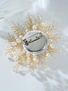 Close-up of luxury snowflake brooch with white pearls and gold wire details