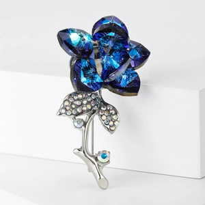Detailed view of dark blue crystal rose brooch with silver rhinestones on white pedestal