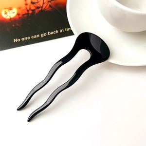 Detail of a minimalist black U-shaped hair pin with wave design for secure bun styling