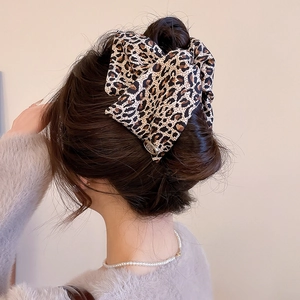 Detail of leopard print bow hair clip with gold metal charm on elegant hairstyle