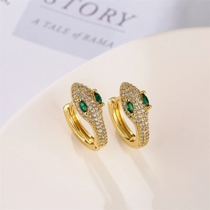 Detail of gold snake earrings with sparkling clear crystals and emerald green stone eyes
