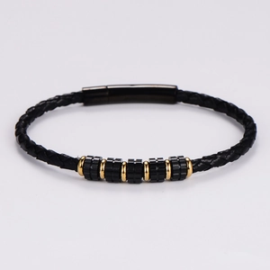 Detalle de una pulsera de cuero trenzado negro para hombre con cuentas de metal dorado