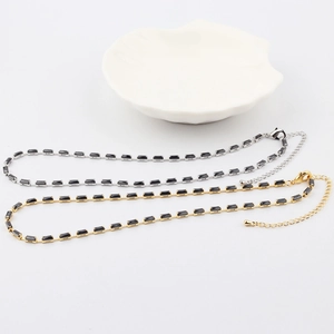 Detail of gold and silver tennis necklaces featuring black rectangular zircon stones