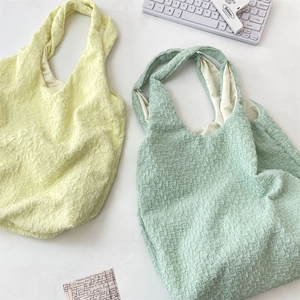 Close-up of pleated texture on light yellow and mint green large canvas tote bags