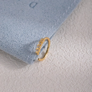 Detailed close-up of a gold-plated wave ring with white zircons on a blue velvet pouch