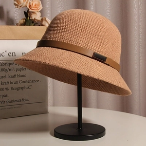 Texture détaillée d'un chapeau de soleil tricoté beige avec une lanière en cuir brun