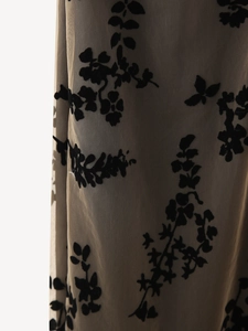 Gros plan sur le tissu en maille avec motif floral floqué noir et texture veloutée