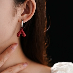 Close-up of red heart pendant earring worn by a model with elegant silver finish details