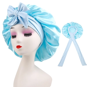 Detail of light blue satin sleep cap with long ribbons and bow on a white background
