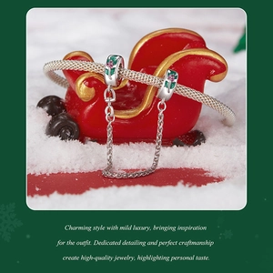 Detail of S925 silver Christmas bracelet with red and green enamel charms on snow