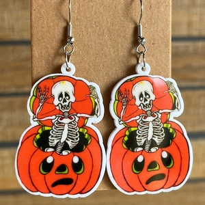 Close-up of Halloween acrylic drop earrings featuring pumpkin and skull cartoon designs