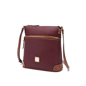 Macro shot of pebble grain leather texture and gold hardware on burgundy crossbody bag