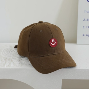 Detail of coffee brown kids baseball cap featuring a red smiley face embroidery patch
