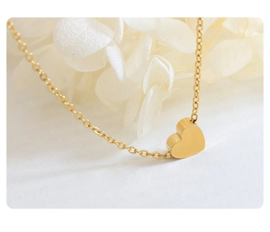 Macro shot of 18K gold plated heart pendant with fine chain on white floral background