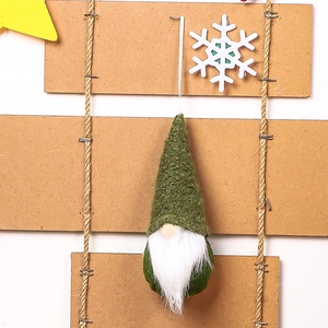 Close-up of a green knitted Christmas gnome ornament with white fur beard hanging on a rope