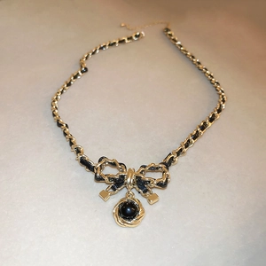 Detail of leather woven chain necklace featuring a bow knot and flower pendant
